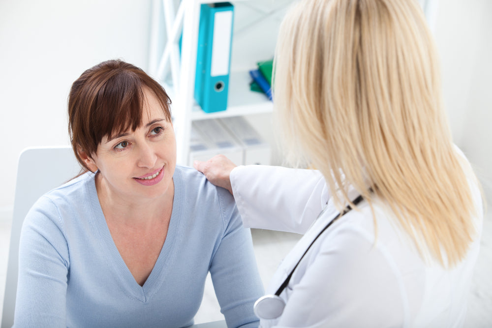 Female Patient Being Reassured By Doctor In Hospital Room